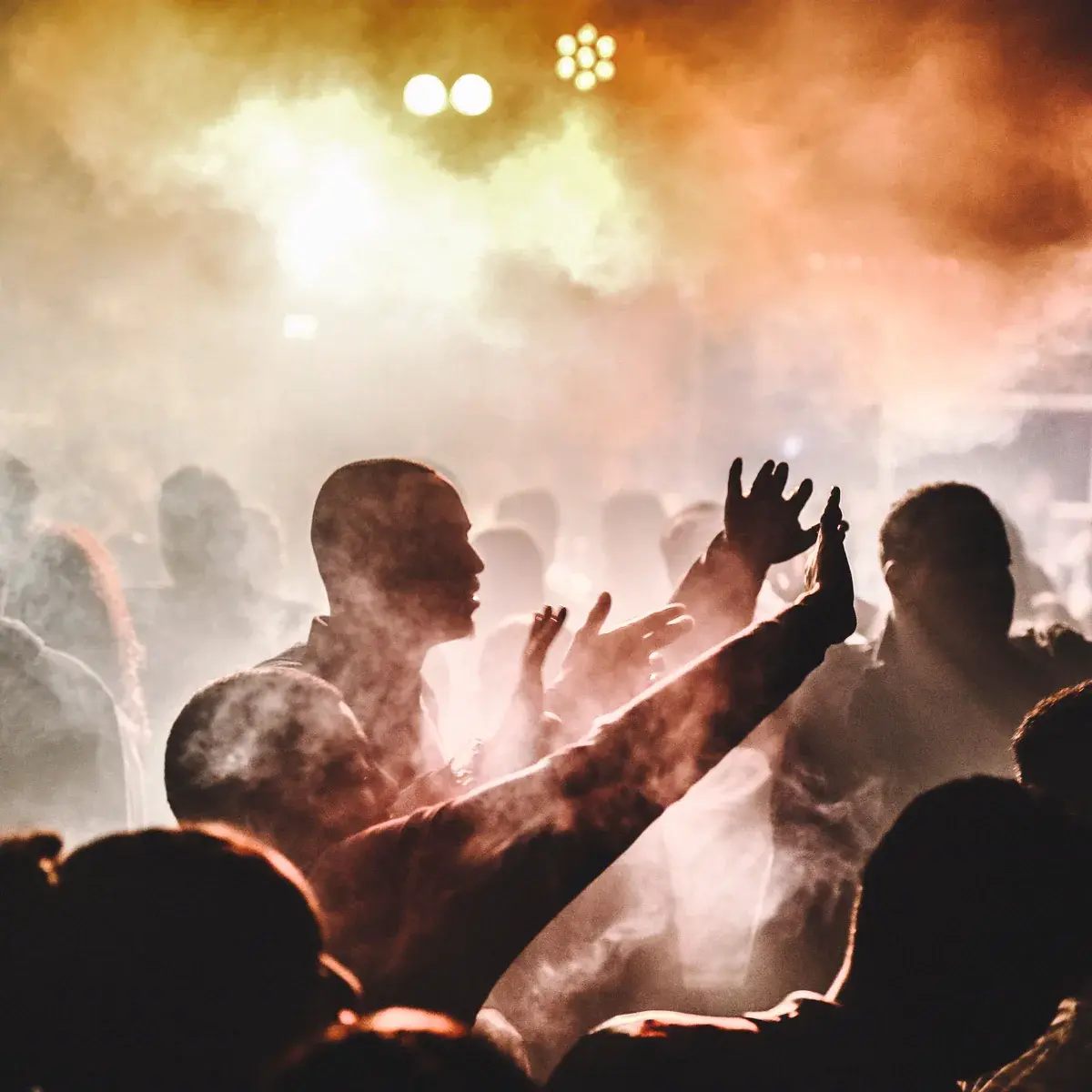 A packed dancefloor under dramatic lighting and haze